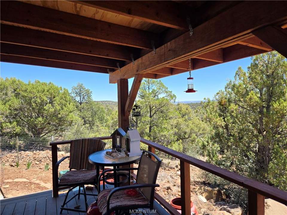 1 bed, 1 bath home on 39.4 acres in Seligman: Covered deck with wood flooring and exposed wood b
